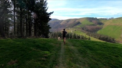 young man trail running in the mointains with his dog