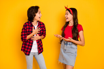 Photo of funny cheerful kids talk look each other laughing have good mood isolated on yellow color...