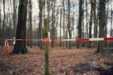 Fototapeta na wymiar way closed by barrier tape in in forest