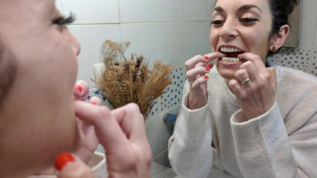 Young woman putting on her orthodontic silicone aligner. Invisible teeth aligner. Mobile orthodontic appliance for dental correction.