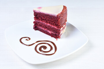 Red velvet cake decorated cake on white plate and light colored wooden background