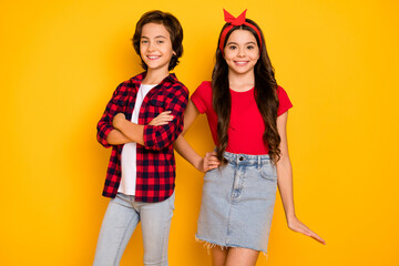 Photo of two children boy crossed hands girl posing wear red casual clothes jeans isolated yellow...
