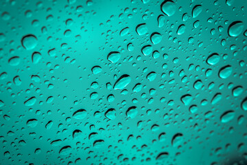 Water droplets scattered on cyan blue glass for background.