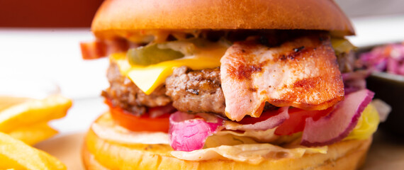Photo of tasty delicious burger with fry potatoes and sauce over white background, fast food.