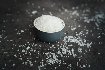 Close up of salt grains in bowl over a dark background