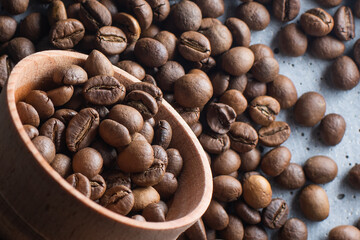 Dark Coffee Beans in a wooden Cup. Symbolic image. Rustic wooden background. Close up. Copy space.