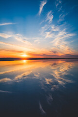 Fototapeta premium 波の水たまりに反射した夕日と空と雲