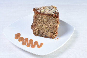 Cake decorated with vanilla and arequipe on white plate and light colored wooden background