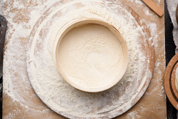 round wooden sieve and white wheat flour on wooden board