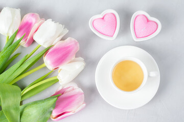 Tulips with white cup of tea on a light background. Spring tenderness still life composition with candles. Flowers for romantic, love atmosphere. Relax, meditation pause. Selective focus, copy space.