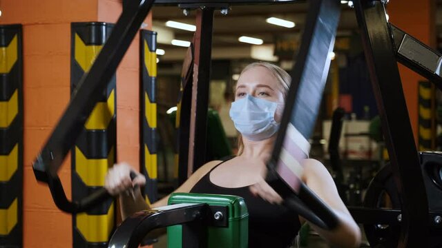 Workout in gym with covid-19 coronavirus precautions, using face mask.