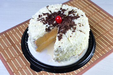 Cake decorated with vanilla and arequipe on white plate and light colored wooden background