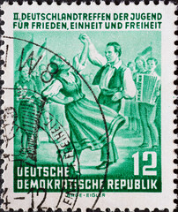 GERMANY, DDR - CIRCA 1954 : a postage stamp from Germany, GDR showing Folk dance couple, young people with flags. Text: II. Germany meeting of young people, Berlin
