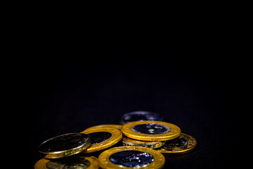 VARIAS MOEDAS DE REAL BRASILEIRO EM FUNDO ESCURO.