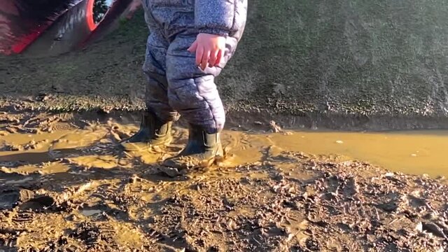 A Toddler Jumping And Playing In A Muddy Puddle. Slow Motion