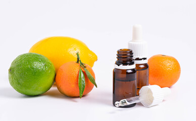 Lime essential oil in glass bottle and fresh green lime fruit isolated on white background.