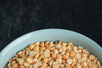 A blue plate with unprepared lentils in a dark background