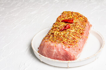 Pork fillet for grilling, baking, or frying with flakes spices in ceramic plate