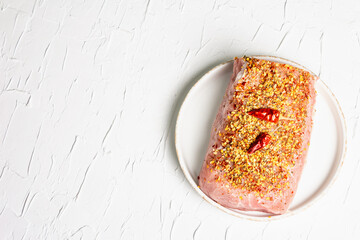 Pork fillet for grilling, baking, or frying with flakes spices in ceramic plate