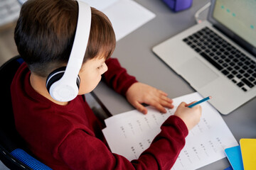Top view of boy doing homework while e-learning