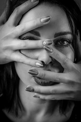 Black and white portrait of a young woman with her face covered with hands, concept for showing the anxieties and fears of women