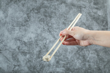 Hand holding a chopstick with a dumpling