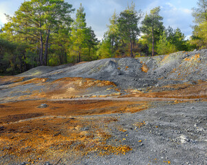 Piles of multicolored rocks in a forest, tailings from pyrite mining at abandoned open pit copper...