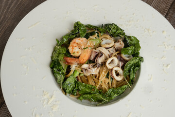 Spaghetti seafood with Basil Leaves ready to eat, wooden background