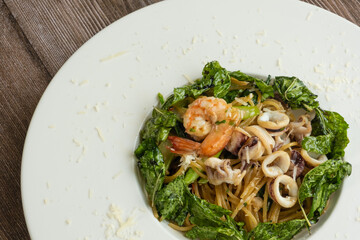 Spaghetti seafood with Basil Leaves ready to eat, wooden background