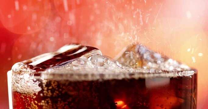 Glass of cola. Ice cola with splashing bubbles slow motion on a blurry light ,blurry background.