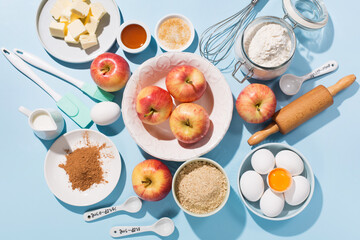 Cooking baking background with ingredients, fresh apples, spices and utensils on blue table.