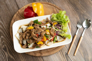 Stir-fried pork with black pepper and basil leaves on wooden background ready to eat
