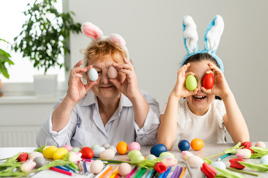 Easter concept. Grandmother with granddaughter are holding Easter eggs at home