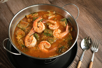 Sour Curry Soup with Shrimp and Vegetable Omelet Cha Om, folk and spoon set up ready to eat - wooden background