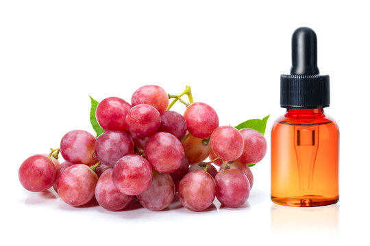 Red grapes seed oil in glass dropper bottle and fresh red grapes isolated on white background.