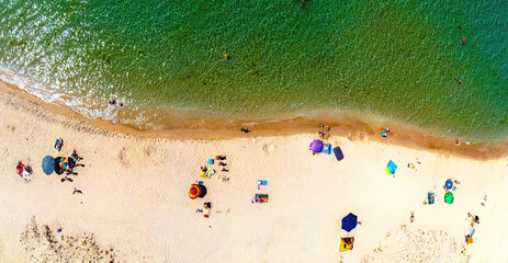 Fototapeta na wymiar Aerial view of sandy beach with tourists swimming in beautiful clear green sea water