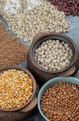 Different kinds of bean seeds, lentil, peas in dishes on a dark background