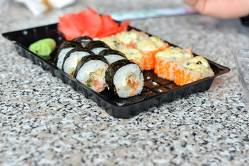 On the table is a saucer with two types of sushi with ginger and wasabi.