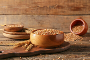 Bowl with wheat grains on wooden background