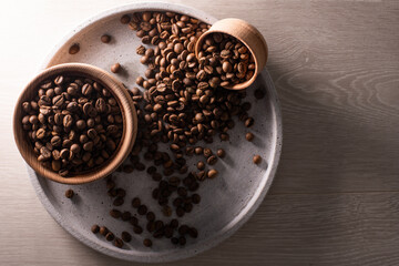 Dark Coffee Beans in a wooden Cup. Symbolic image. Rustic wooden background. Close up. Copy space.