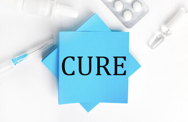 On a white background, a syringe, ampoule, pills, a vial of medicine and light blue stickers with the inscription CURE. Medical concept