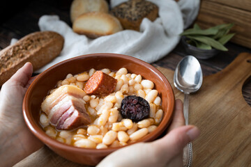 Hands hold a plate of Asturian bean stew ready to eat. Typical dish of the north of Spain. Food photography