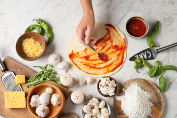 Woman making pizza on light background