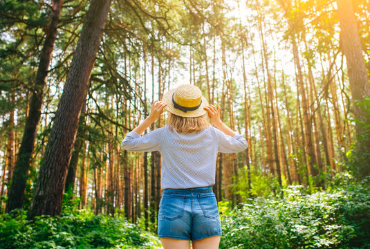 Hipster girl in straw hat standing in the forest. Wanderlust concept. Travelling ideas. Beautiful woman in the nature. Summer vibes.
