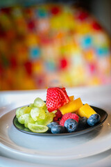 Pieces of various fruits and berries on a black plate