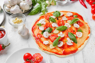 Tasty raw pizza on light background