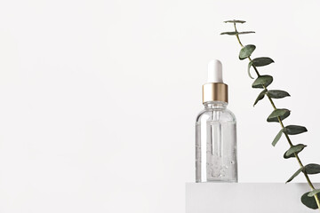 Natural skin care products concept. Herbal mineral cosmetics, serum, hyaluronic acid on white podium. Transparent dark glass bottle with dropper, copy space