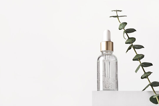 Natural Skin Care Products Concept. Herbal Mineral Cosmetics, Serum, Hyaluronic Acid On White Podium. Transparent Dark Glass Bottle With Dropper, Copy Space