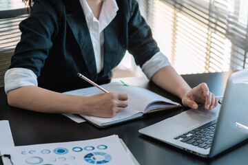 Businesswoman use the concept of work by taking  notes and laptop at the office.
