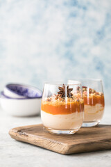 Autumn trifle dessert. Layered pumpkin parfait , pecan nut dessert in a glass, with autumn decorations.